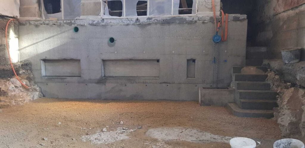 neue Stützmauer aus gestocktem Beton mit Nischen